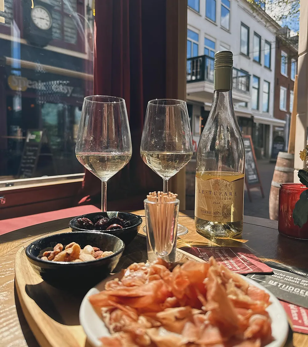 Witte wijn en een bord prosciutto bij het raam